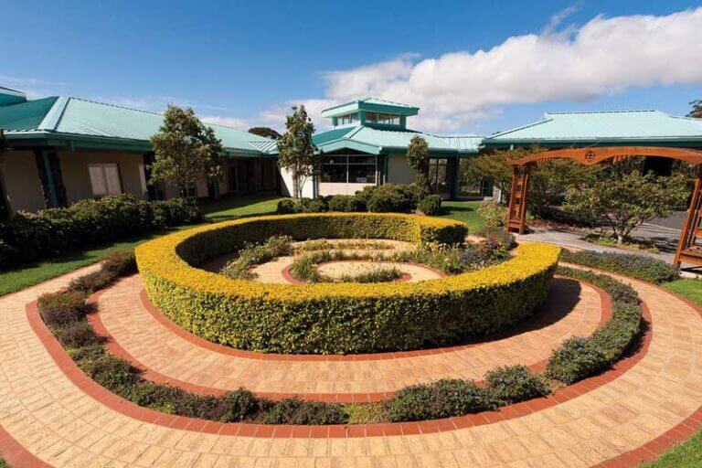 Exterior shot of Queen's North Hawaii Community Hospital with a garden in the foreground.